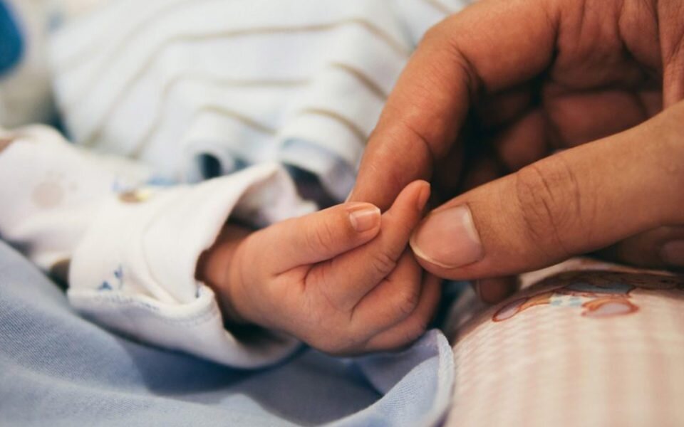 Adult holding a child's hand in hospital