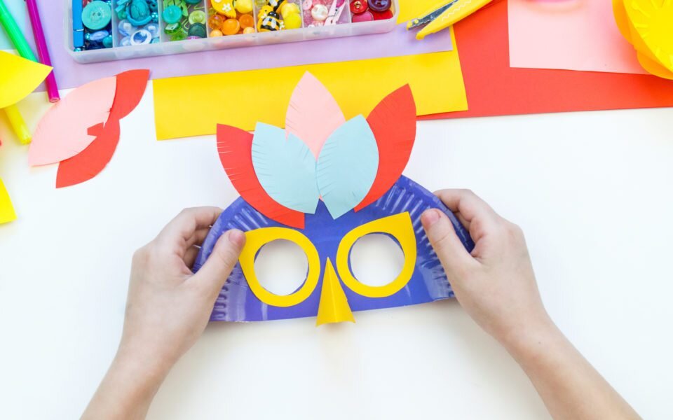 A child makes a bird mask out of paper.