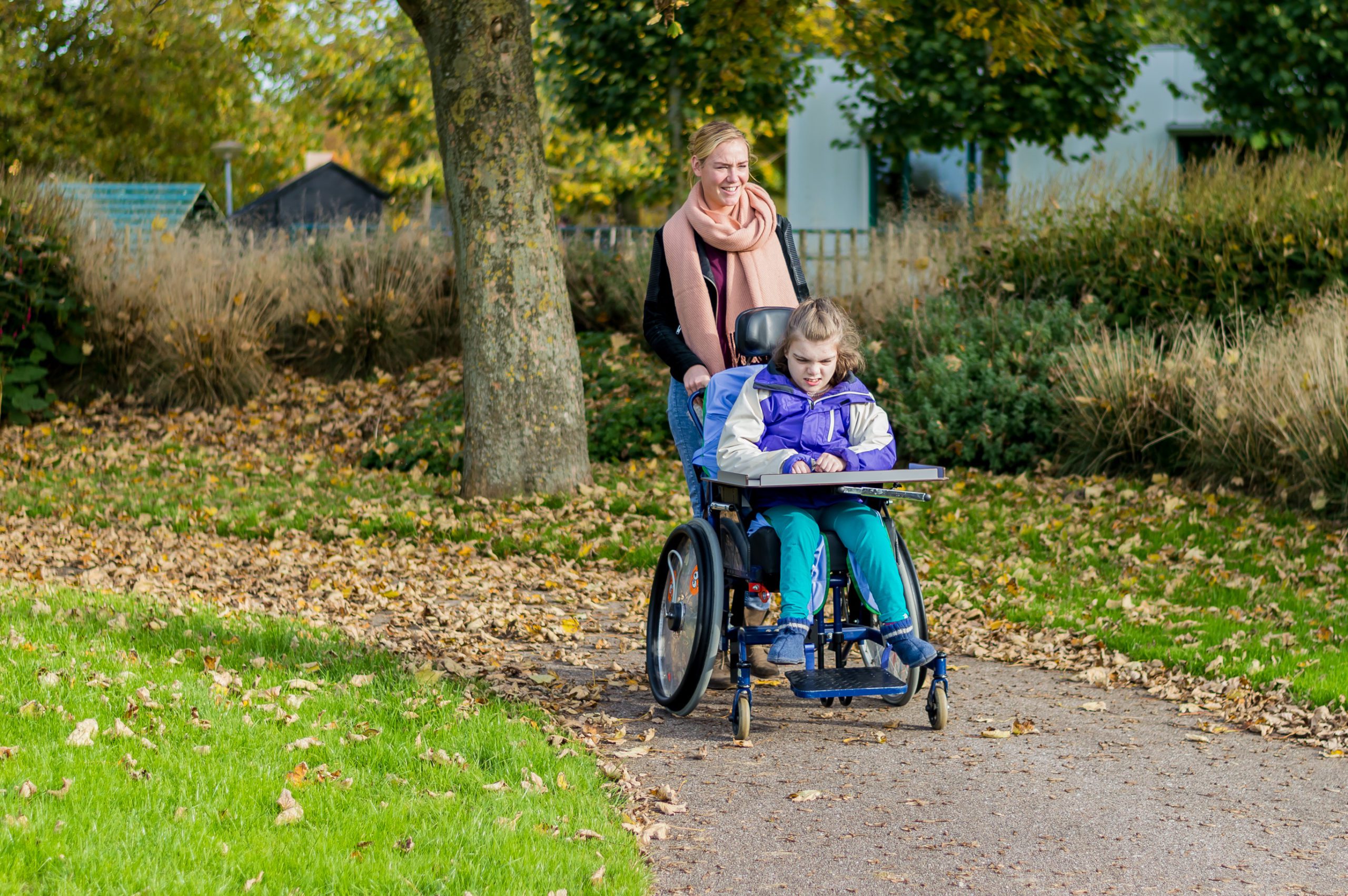 woman pushing girl in a wheelchair in a park