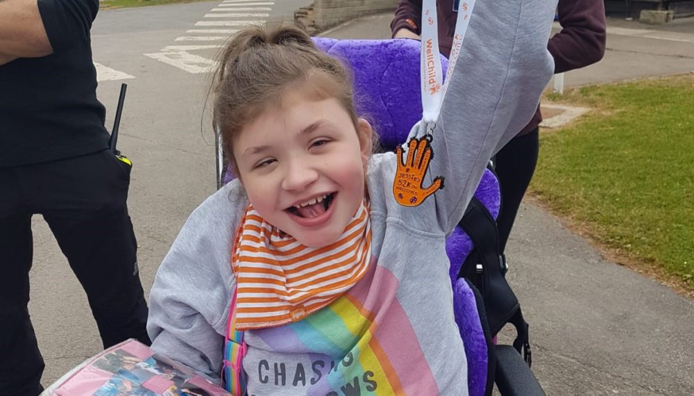 Jessie holding the Step Up medal she designed