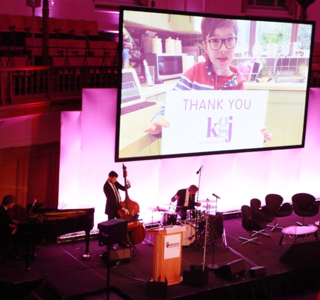 Noah holding a piece of paper thanking KJG for their support of WellChild