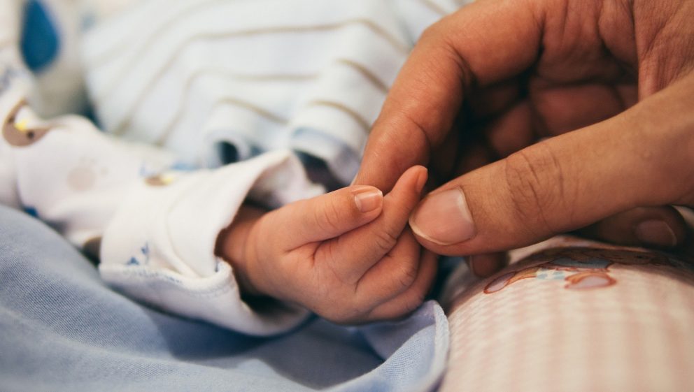Adult holding a child's hand in hospital