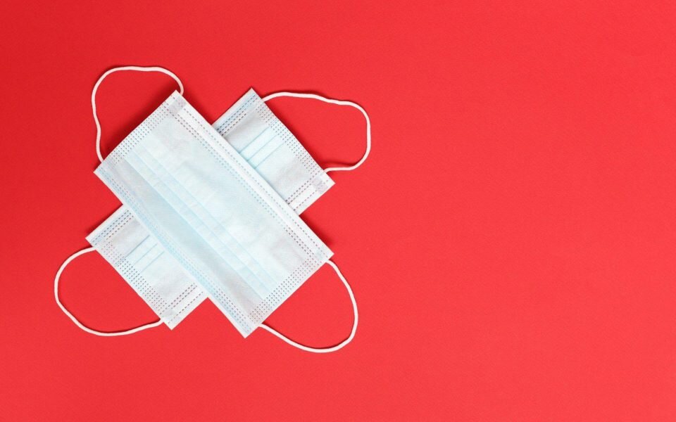 Two face masks in the shape of a cross on a red backgroun