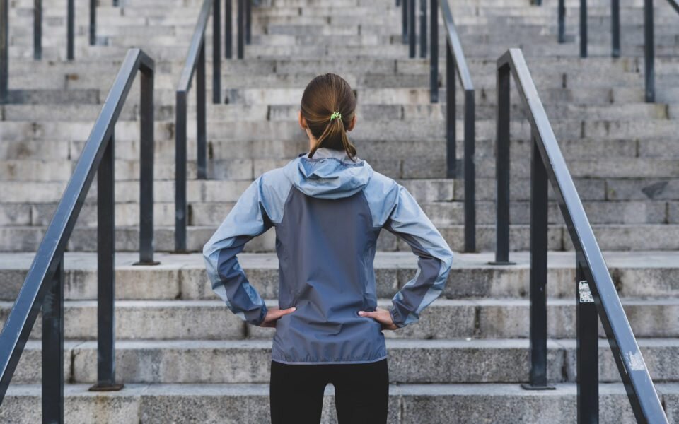 Woman with hands on her hips looking up some concrete steps