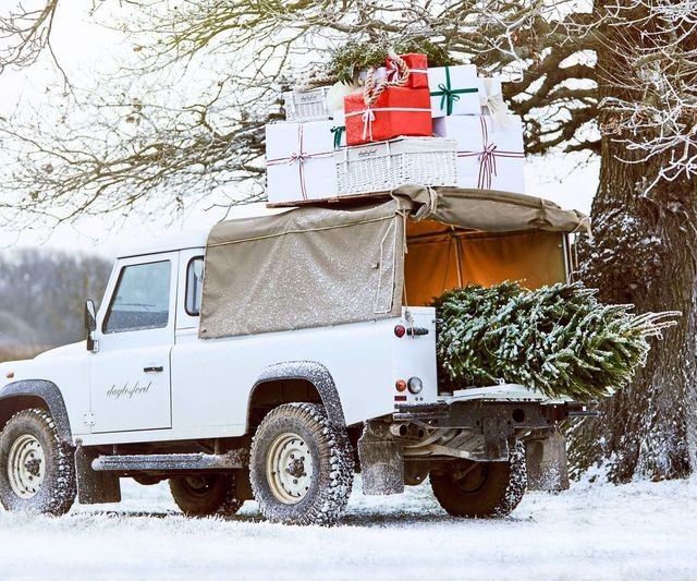 Truck in the snow with Christmas tree in the boot and presents on the roof