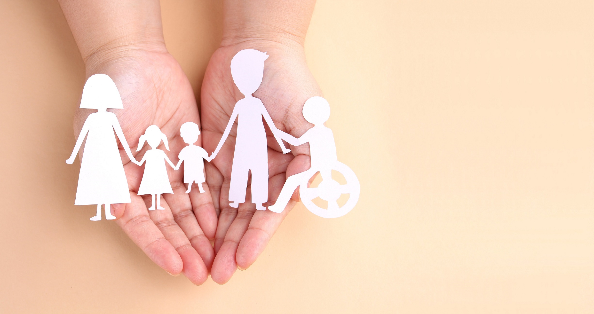 hands holding paper cut out of family, including child in wheelchair