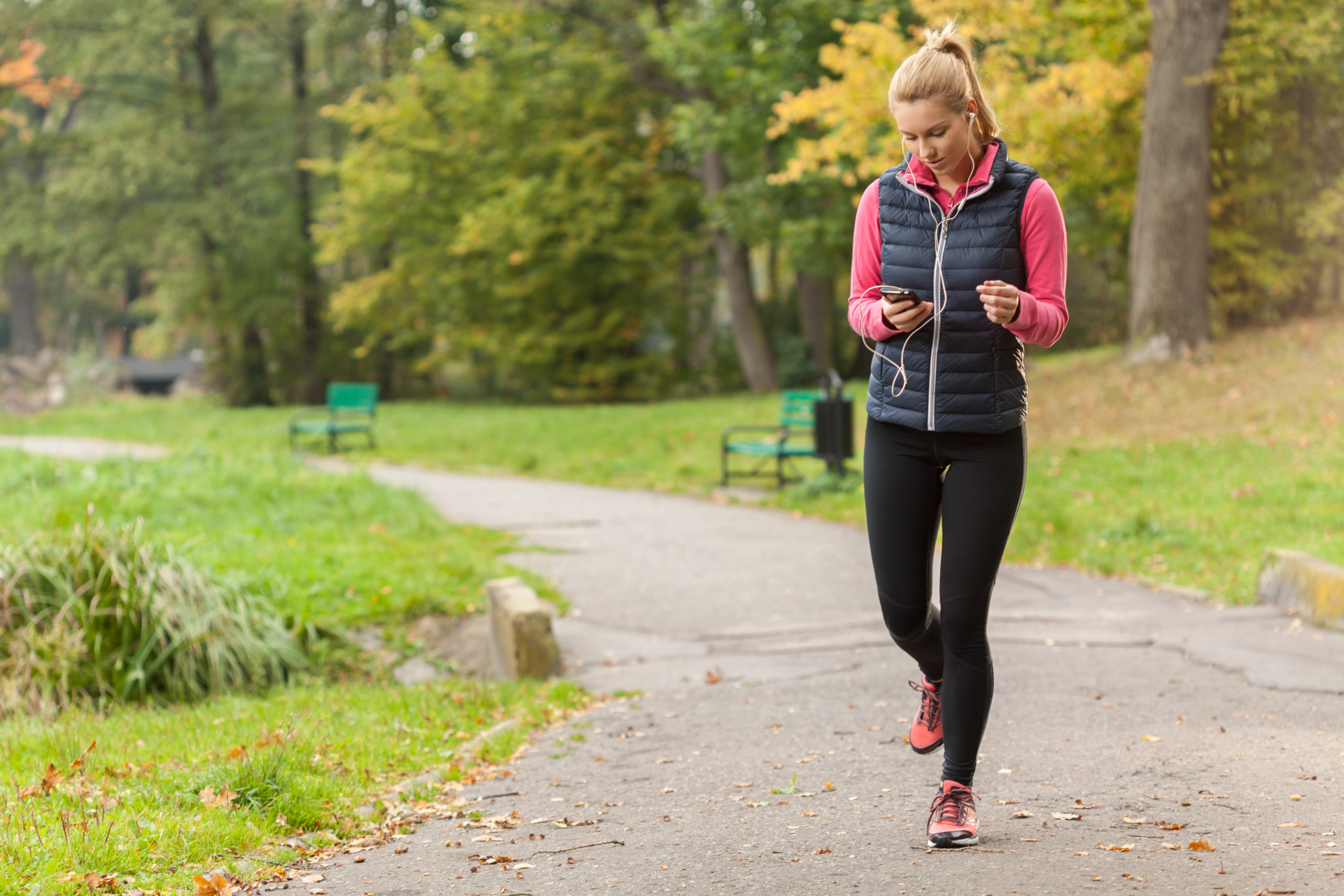 woman walking in the park listening to music, podcasts or audiobooks