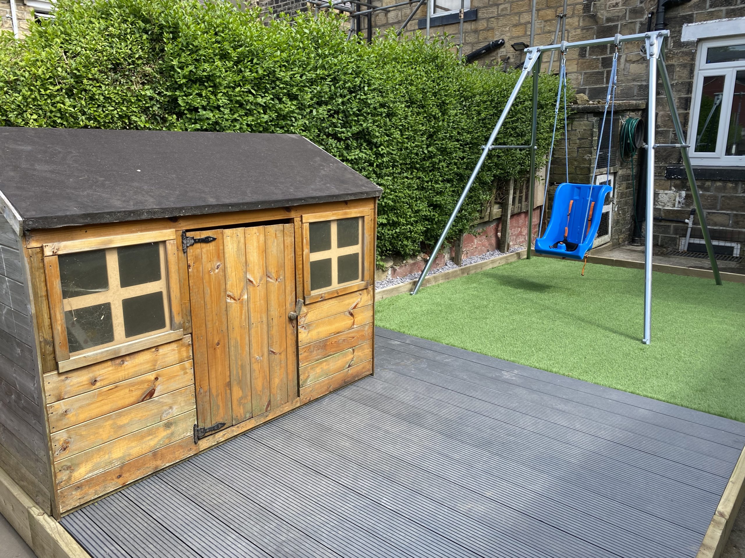 Garden transformation featuring artificial grass, a playhouse and blue swing