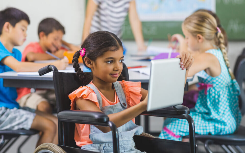 Disabled schoolgirl using digital tablet in classroom at school