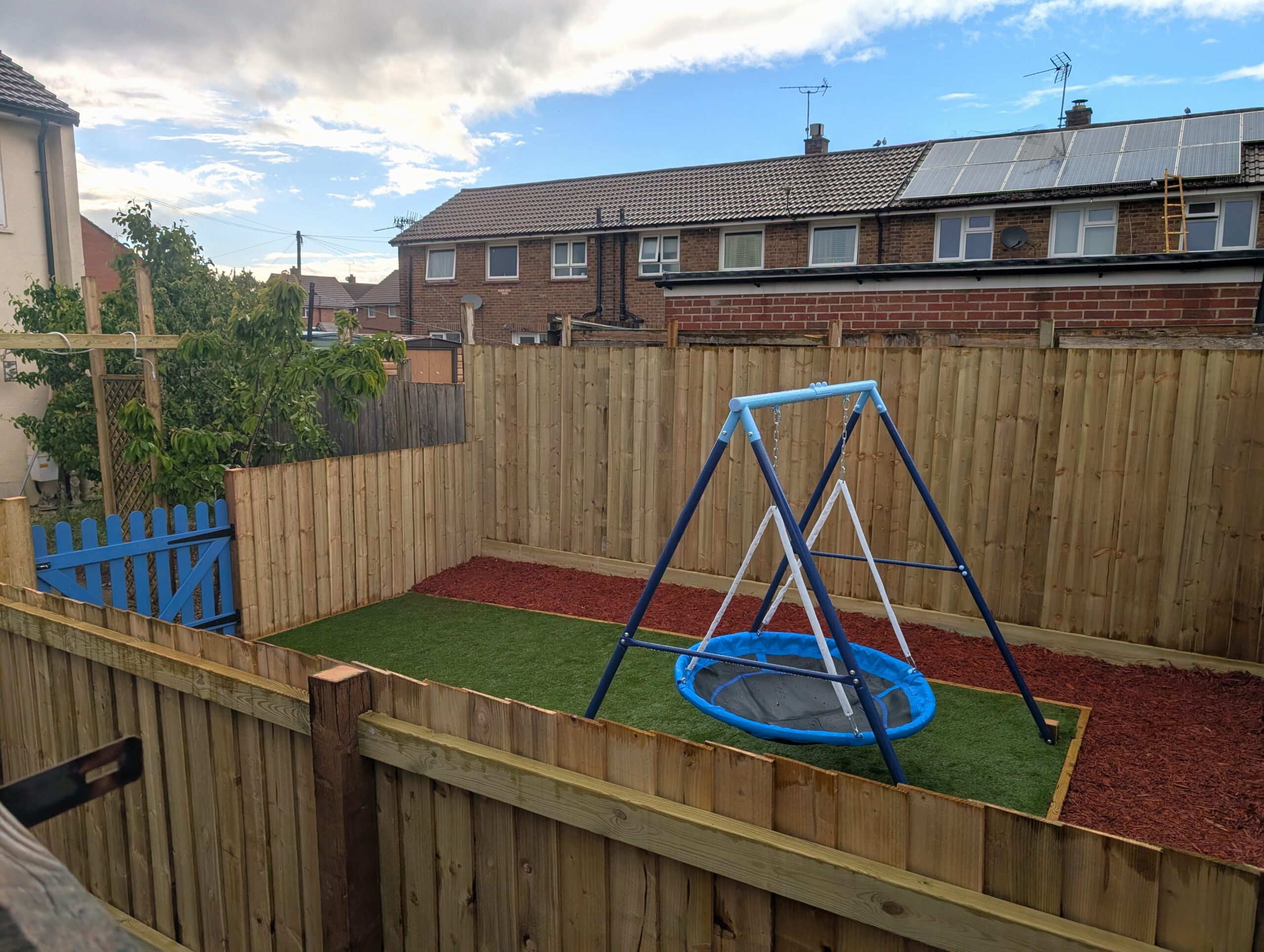 Child's play area with swing set on grass area with new fencing.